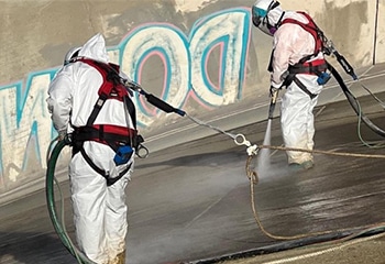 Two workers removing lead-based paint from Prado Dam